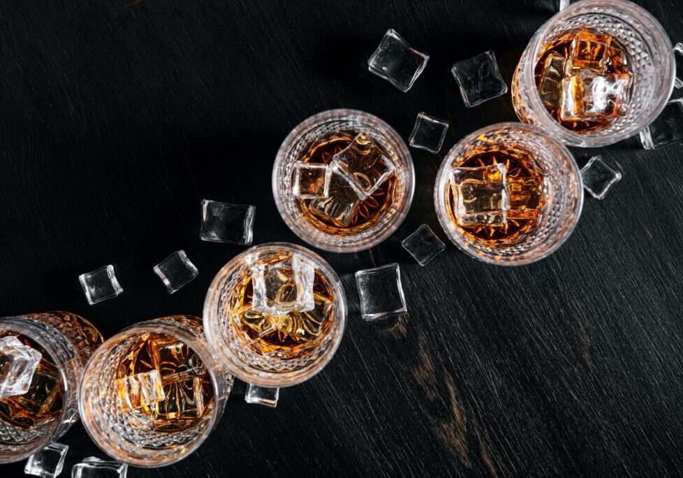 Whiskey Use Whiskey glasses lines up next to each other with ice cubes around them