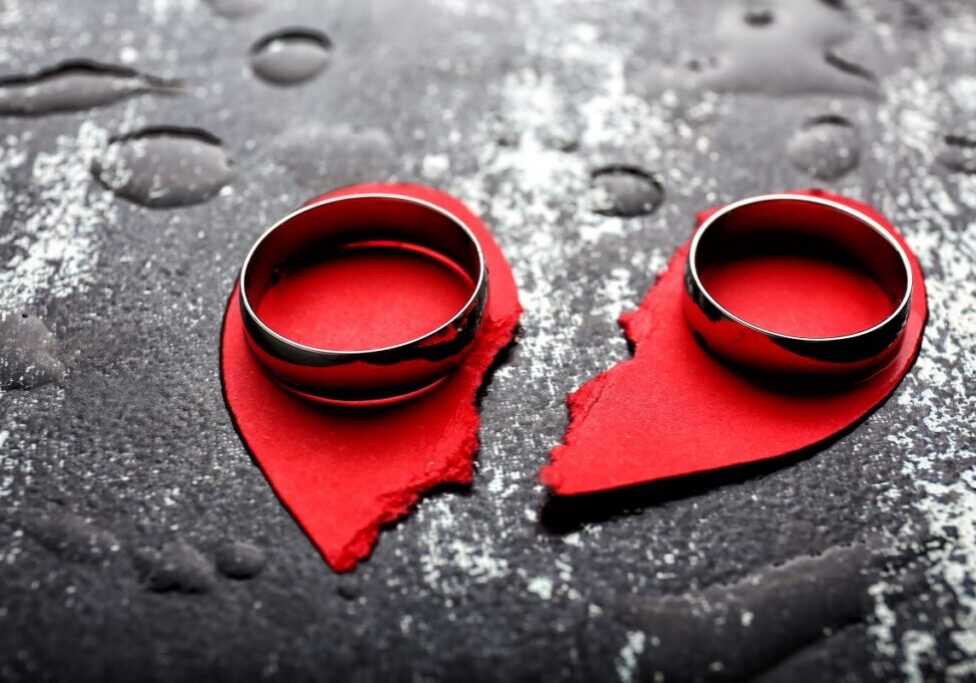 divorce Torn paper heart with a wedding band sitting on each half