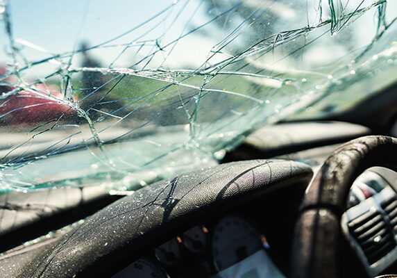Photo of the inside of a car in an accident with a broken windshield from the perspective of the driver