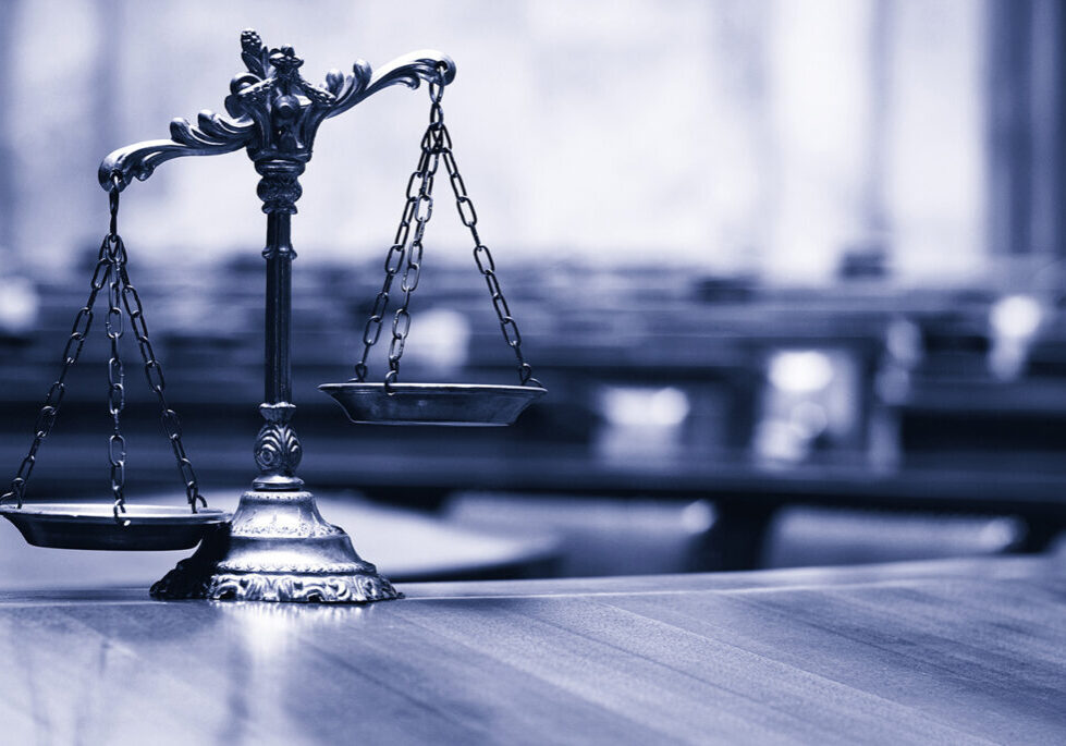 Image of a justice scale sitting on a courtroom desk